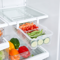 Clear pull-out bin sliding from a fridge shelf holding fresh vegetables