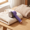 Lint shaver resting on a folded wool jumper on an oak table