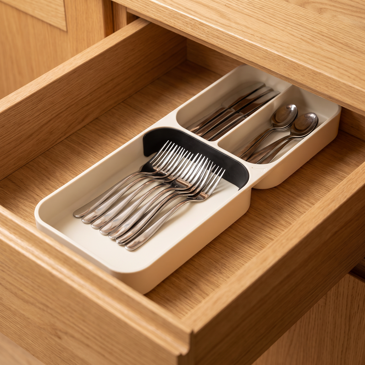 Cutlery tray inside an open oak kitchen drawer with sorted cutlery
