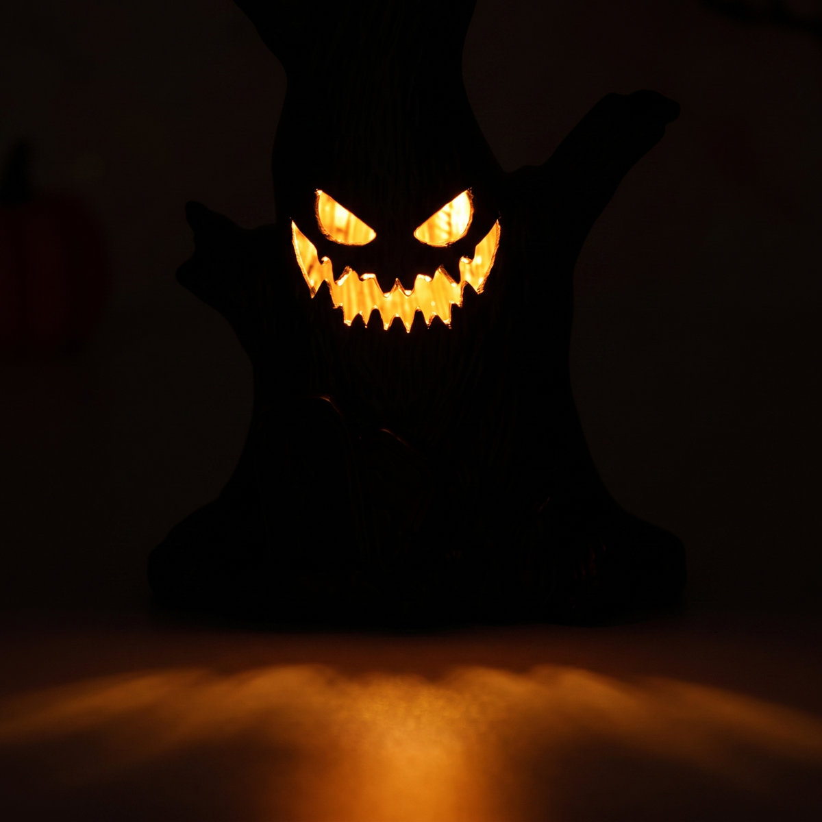 Close-up of the Luniee Pumpkin Lamp carved face glowing in a dark room